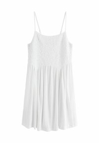 Robe blanche avec un corsage texturé, des bretelles spaghetti et une jupe fluide. Le matériau est léger et légèrement froissé.