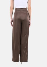Pantaloni marroni a vita alta e gamba larga realizzati in tessuto morbido. Presentano un design pulito senza tasche visibili o decorazioni.