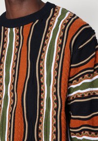 Strickpullover mit kräftigen vertikalen Streifen in Schwarz, Orange, Grün und Weiß, mit strukturierten Mustern und geripptem Ausschnitt.