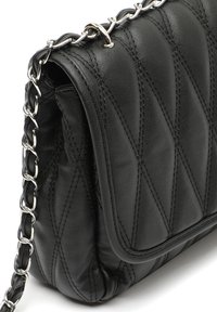 Borsa a tracolla in pelle nera trapuntata con una tracolla in metallo argentato. Presenta cuciture diagonali e una chiusura a pattina per un tocco di texture e dettaglio in più.