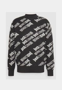 Svart långärmad tröja med ribbad krage, manschetter och nederkant, mönstrad diagonalt med vitt upprepande "Just Cavalli"-text.