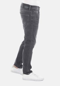 Jeans de mezclilla gris con corte recto, cinco bolsillos y parche con logo en la cintura trasera, combinados con zapatillas blancas.