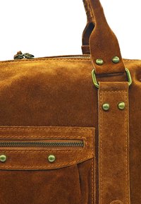 Sac en daim marron avec une finition texturée, doté d'une poche zippée à l'avant et de accents en laiton. Sangle robuste incluse.