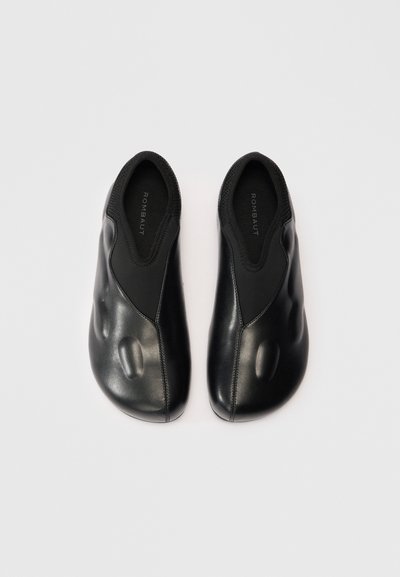 Scarpe slip-on nere con un design elegante, realizzate in pelle liscia, con parte superiore testurizzata, punta arrotondata e dettagli di cucitura minimi.