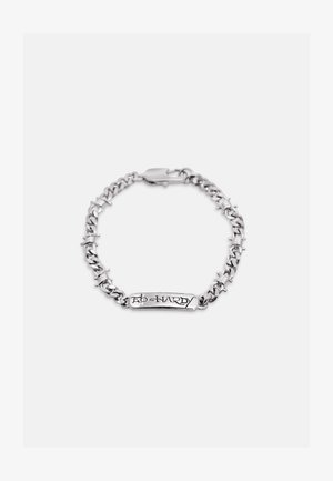 Hõbedast ketiga käevõru, millele on graveeritud „ED HARDY“, kaunistatud okastraadi motiividega ja kinnitatav lattkinnitusel.