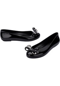Le ballerine in vernice nera presentano una punta arrotondata e un fiocco decorativo con accenti metallici sulla parte anteriore. Superficie liscia, design minimalista.