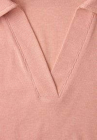 Zbliżenie na różowy prążkowany materiał z głębokim dekoltem w kształcie litery V oraz detalem kołnierzyka.