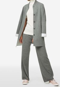 Gray wool-blend coat with a button front, oversized fit, and ribbed collar. Paired with matching gray wide-leg pants and light pink sneakers.