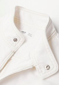 Collet et partie supérieure avant d'une veste en denim blanc avec des boutons-pression argentés, une fermeture éclair et une étiquette de marque indiquant "MNG Denim" taille petite.