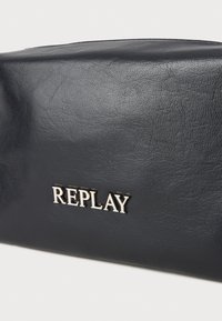 Monedero de cuero azul marino con una textura suave y el logo plateado "REPLAY". Forma rectangular con bordes redondeados y cierre con cremallera en la parte superior.