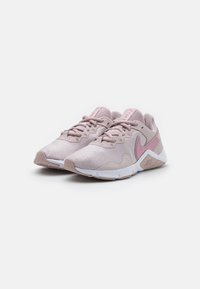 Zapatillas deportivas de color rosa claro con parte superior de tela texturizada, suela blanca y detalles en rosa. Presentan un diseño con cordones y patrones hexagonales en los laterales.