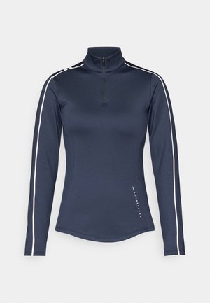 Navy long-sleeve athletic top with a quarter-zip collar, white side stripes, smooth texture, fitted design, and logo detail at the hem.