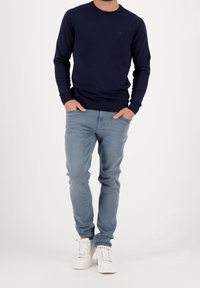 Mörkblå tröja med rund halsringning, kompletterad med ljusblå jeans och vita sneakers. Enkelt mönster och mjuk textur genomgående.