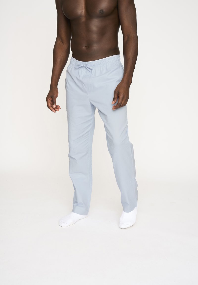 Lyseblå, letvægtsbukser med elastisk talje og snoretræk. Blød tekstur, lige ben-design med sidelommer.