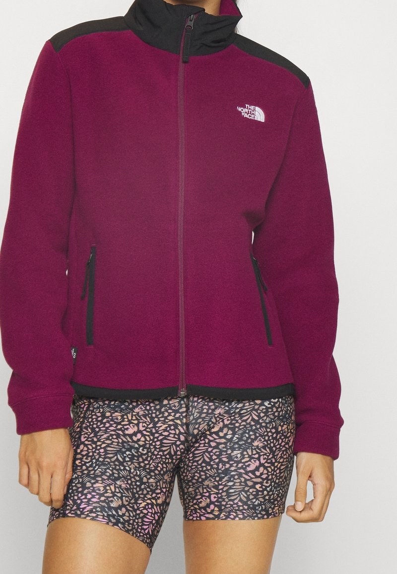 Fleecejacka i mörk magenta med svarta detaljer, full dragkedja och två sidofickor. Matchad med mönstrade tajta shorts i rosa och svart.