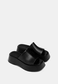 Sandali platform neri con tomaia in pelle liscia, design open toe e suola spessa in gomma nera, caratterizzati da uno stile minimalista e senza hardware visibile.