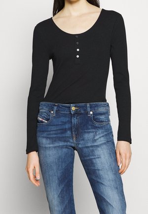 Black ribbed long-sleeve top featuring a scoop neckline and four button placket, paired with blue denim jeans showing subtle fading.