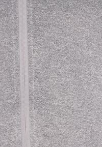 Tessuto a maglia grigio con dettaglio della zip verticale al centro. Texture morbida con un aspetto uniforme.