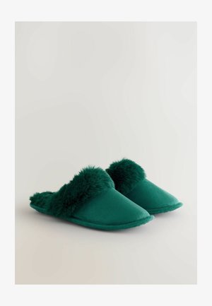Zelené pantofle s hladkým textilním svrškem a měkkým, huňatým lemováním. Mají design na nazouvání a špičatý tvar špičky.