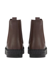 Botas de cuero marrón hasta el tobillo con paneles laterales elásticos, suelas de goma texturizada negra en contraste y lengüetas traseras para facilitar su colocación.