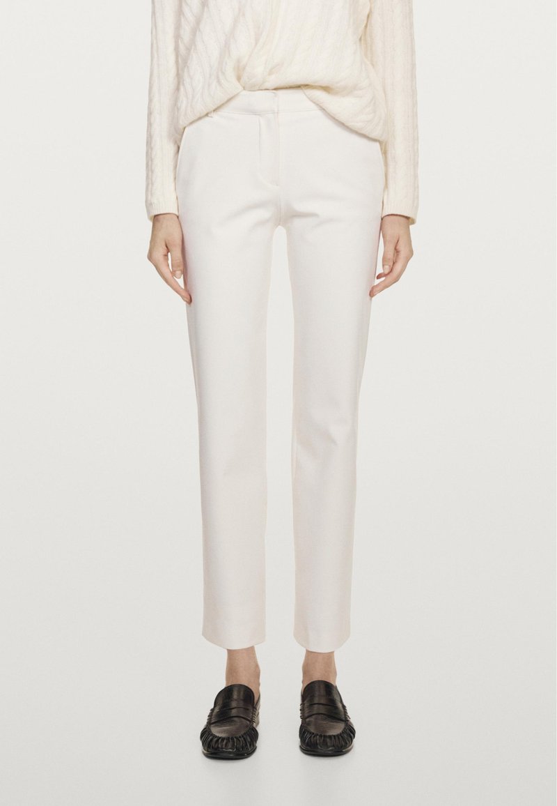 Witte, op maat gemaakte broek met een smalle pasvorm, gladde textuur, zonder zichtbare zakken, gecombineerd met zwarte loafers met een franjerand.