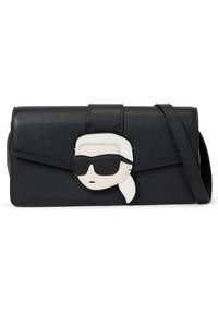 Czarna skórzana torba na ramię o teksturowanym wykończeniu, z białą i czarną karykaturą na przodzie oraz z magnetycznym zapięciem.