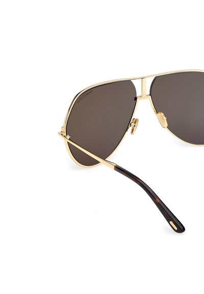 Pilotské sluneční brýle se zlatým kovovým rámem, tmavými skly a sklopnými stranami s želvovinovým vzorem, vybavené gumovými nosníky pro pohodlí.