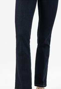 Tmavě modré džínové kalhoty slim fit, s kontrastním světlým prošitím a čistým lemem. Textura je hladká s mírným strečem.