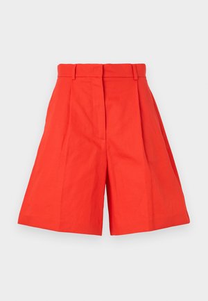 Red cotton shorts with a high waist, featuring pleats and a wide-cut silhouette. Smooth texture and clean lines. No pockets or embellishments.