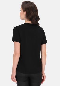 Sort kortærmet t-shirt med rullede ærmer, lavet af blødt stof. Har en rund halsudskæring og en afslappet pasform, set fra ryggen.