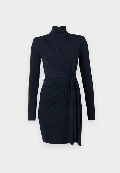 Navy zila gara piedurkne kleita ar augstu dekoltē, ar savelktām auduma detaļām un mezglu jostasvietā, izgatavota no gludas, elastīgas vielas.