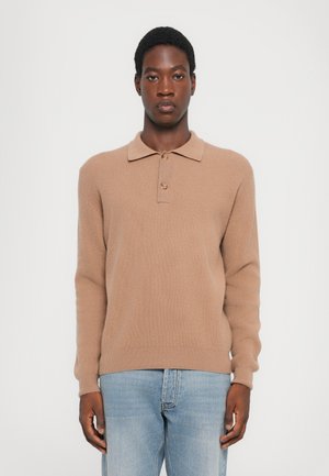 Tan ribbed polo sweater with a collar and three buttons, worn with blue jeans. Soft texture, long sleeves, slim fit design.