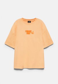 T-shirt à manches courtes de couleur pêche avec col rond, texte orange "L'ORANGE FRUIT" et un petit graphisme de tranche d'orange au centre devant.