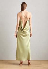 Satinė žalia be nugaros slip su cowl gaminiu. Plonos reguliuojamos petnešėlės ir elegantiška siluetas. Lygus, teka tekstūra.
