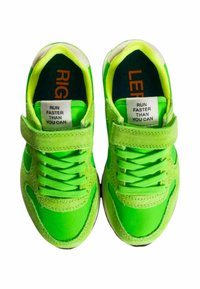 Sneakers verdi con strap in velcro, design con lacci e tomaia in tessuto. Presentano accenti e etichette di un brillante verde con la scritta "SINISTRA" e "DESTRA."