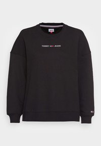Felpa nera con collo rotondo con il logo "Tommy Jeans" e la bandiera centrati sul petto, polsini e orlo a coste, e una piccola bandiera sul polsino sinistro.