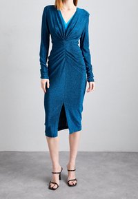Långärmad klänning med V-ringning i blå glittrig tyg, med en rynkad framtill, slank siluett och en hög slits vid fållen.