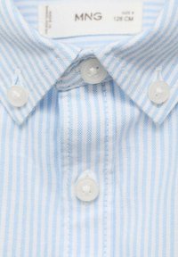 Cămașă din bumbac cu dungi albastre deschise și albe, dotată cu guler ascuțit, trei butoane albe și o textură moale. Etichetă marcată "MNG".