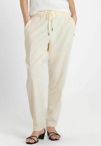 Lichtbeige pull-on broek met een elastische tailleband, een trekkoord, zijzakken en een gladde, licht glanzende stofafwerking.