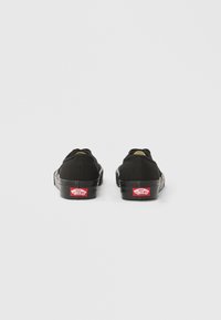 Baskets en toile noire au design profil bas, bout arrondi et semelle en caoutchouc contrastante. Présentent des accents de logo rouges au talon.