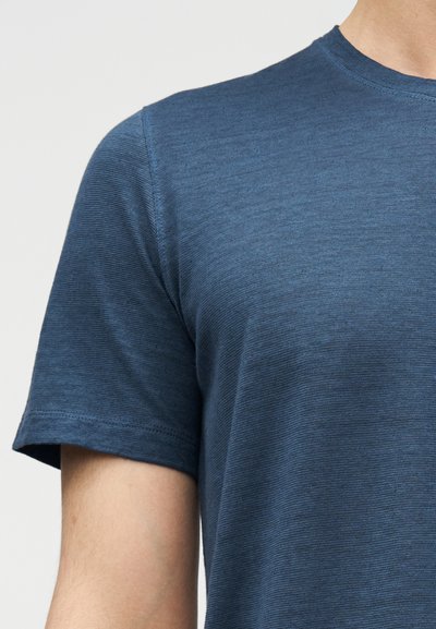 Μπλουζάκι μπλε με κοντά μανίκια, κατασκευασμένο από μαλακό, υφασμένο ύφασμα· διαθέτει στρογγυλή λαιμόκοψη και ενισχυμένες ραφές στα μανίκια και το τελείωμα.