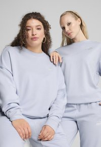 Felpa e pantaloni azzurro chiaro realizzati in morbido materiale, caratterizzati da una vestibilità rilassata, colletto tondo e un logo discreto sul petto.