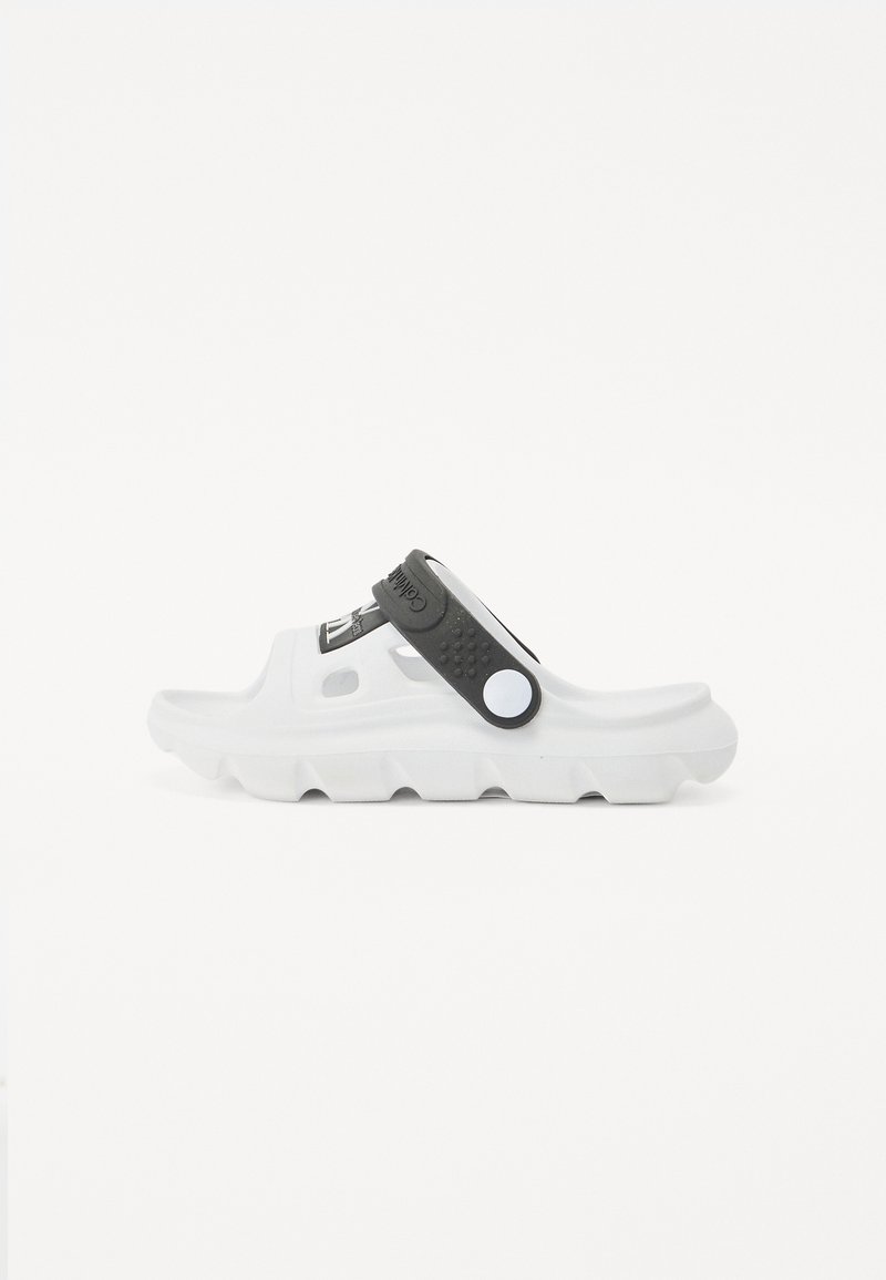 Sandale à glissière blanche avec une bride noire texturée et un bouton circulaire blanc. Dispose d'une semelle épaisse avec un design cranté.