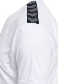 Witte overhemdsmouw met een zwarte streep met witte gestippelde chevronpatronen op de schouder.