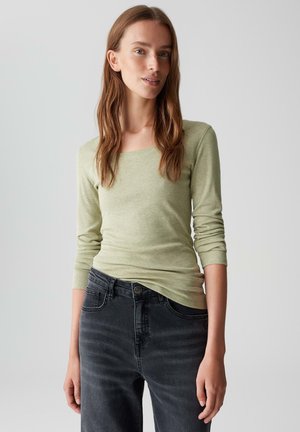 Lichtgroene, lange mouwen shirt met vierkante halslijn en getailleerd ontwerp, gecombineerd met donkergrijze jeans met vijf zakken en een knoopsluiting.