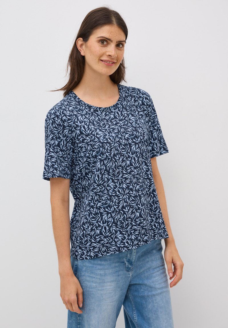 Camiseta navy de manga corta, con cuello redondo y un patrón de hojas blancas. Hecha de material suave y ligero con un corte holgado.