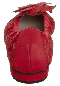 Ballerines rouges en suede doux avec un bout rond, ornées d'une accent floral 3D à l'avant et d'un motif texturé sur les côtés.