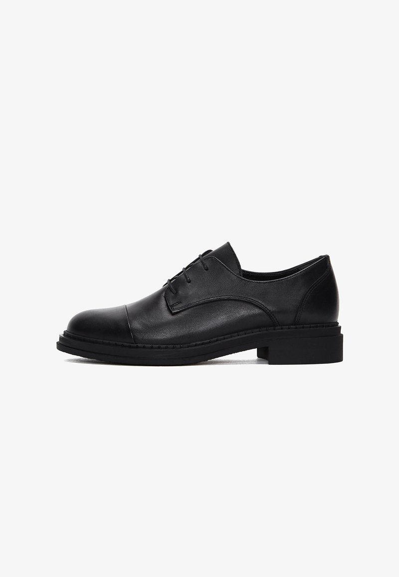 Chaussure habillée pour homme en cuir noir avec lacets à l'avant, talon bas empilé et bout arrondi sur fond blanc.