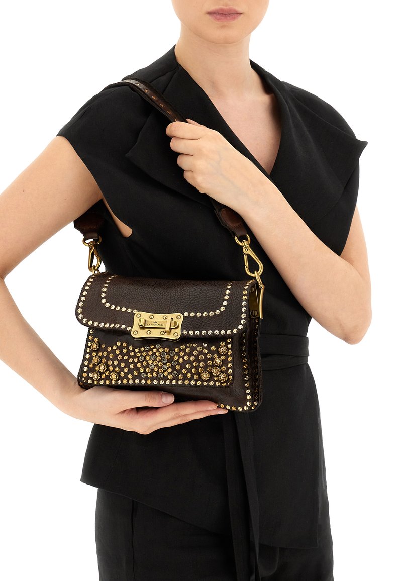 Borsa a mano in pelle marrone con borchie dorate, chiusura a patta e tracolla removibile. Superficie strutturata con dettagli decorativi.