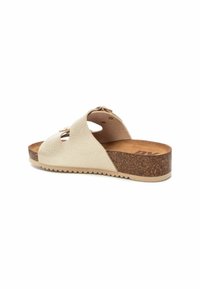 Sandal de color beige claro con un upper texturizado, diseño de punta abierta y un tacón de cuña de corcho. Presenta recortes y una suela de goma con un patrón de olas.